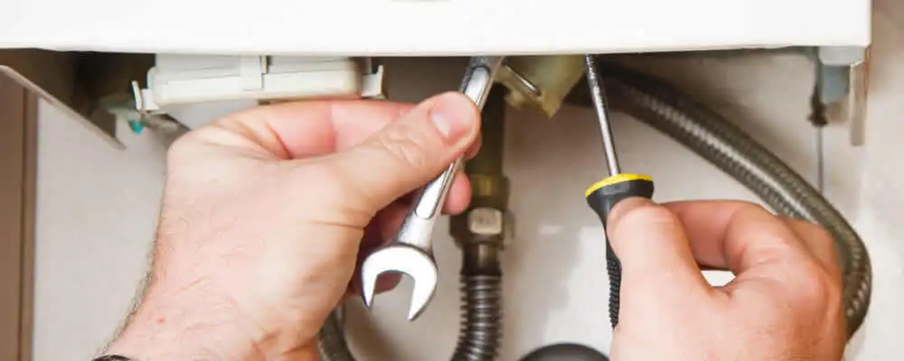 Boiler repair technician tightening pipe fittings and connections in Aurora, CO