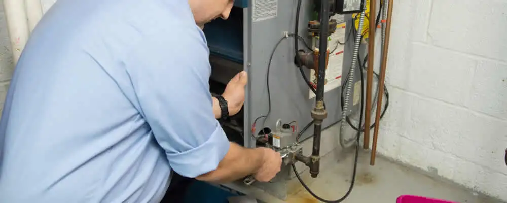 Furnace repair technician inspecting and servicing a home heating system in Aurora, CO