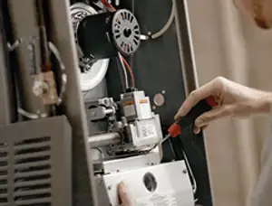 Furnace repair technician inspecting internal components and wiring in Aurora, CO