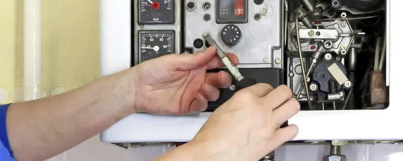 Heating repair technician adjusting boiler controls and components in Aurora, CO