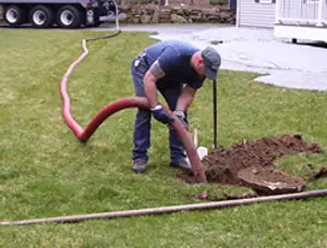 Septic pumping technician servicing a residential septic tank with a vacuum hose in Aurora, CO