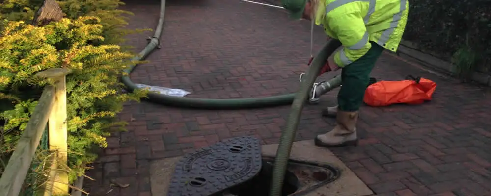 Septic tank cleaning technician servicing a septic tank with a vacuum hose in Aurora, CO