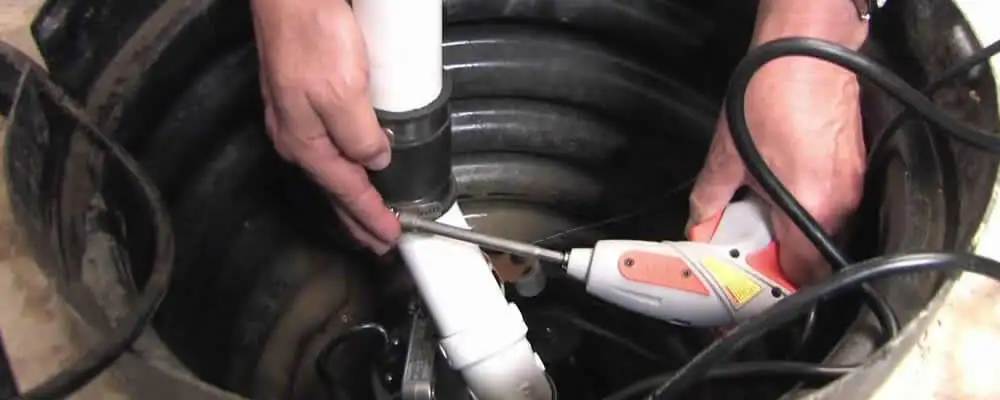 Sump pump installation technician connecting PVC discharge piping in Aurora, CO