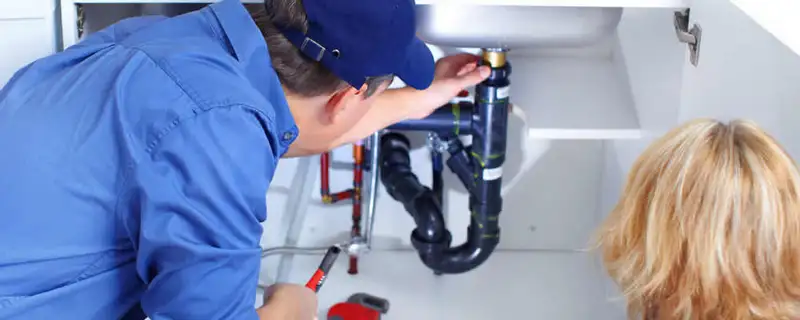 Plumber repairing under-sink drain pipes and fittings in Aurora, CO